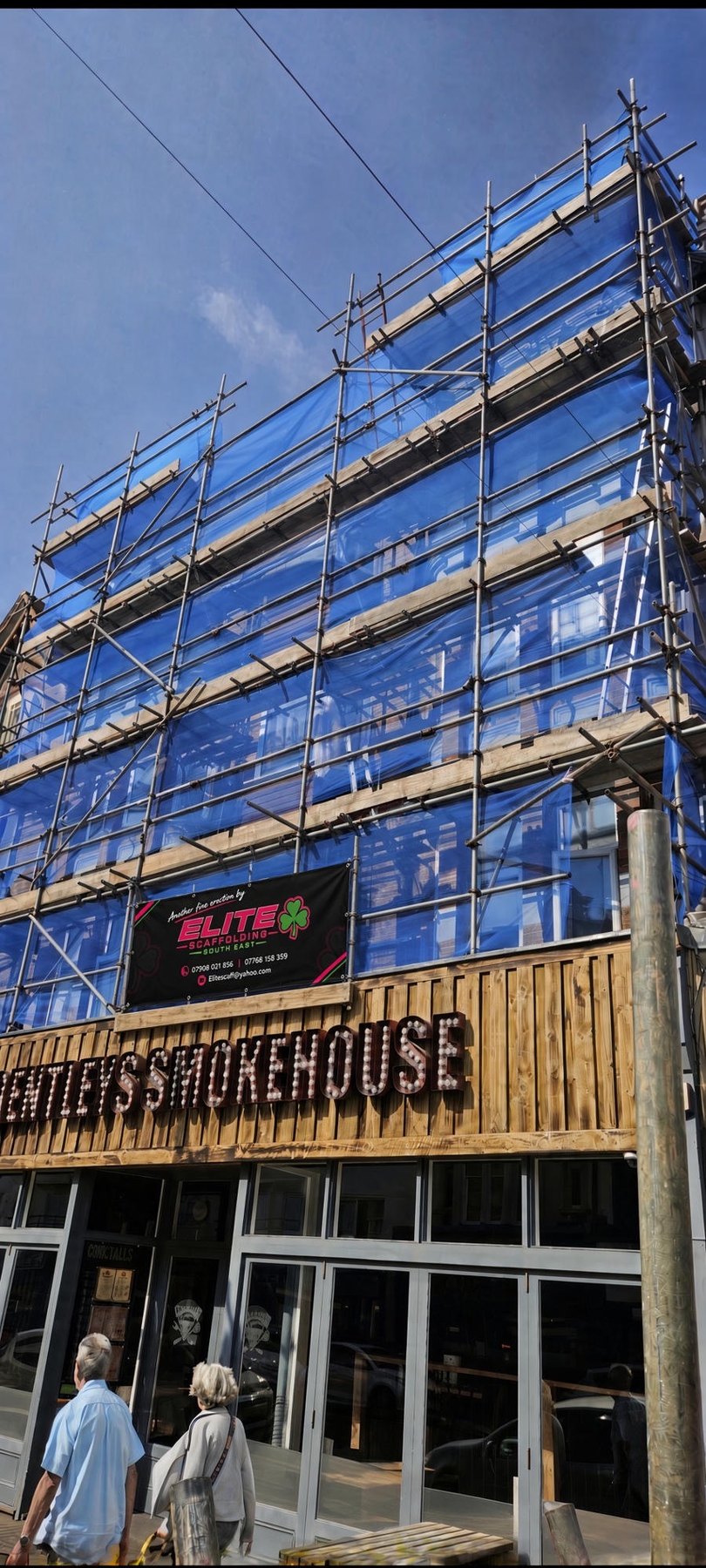 Debris-netted scaffold over Bentley's Smokehouse in Hastings, Elite banner on the lift