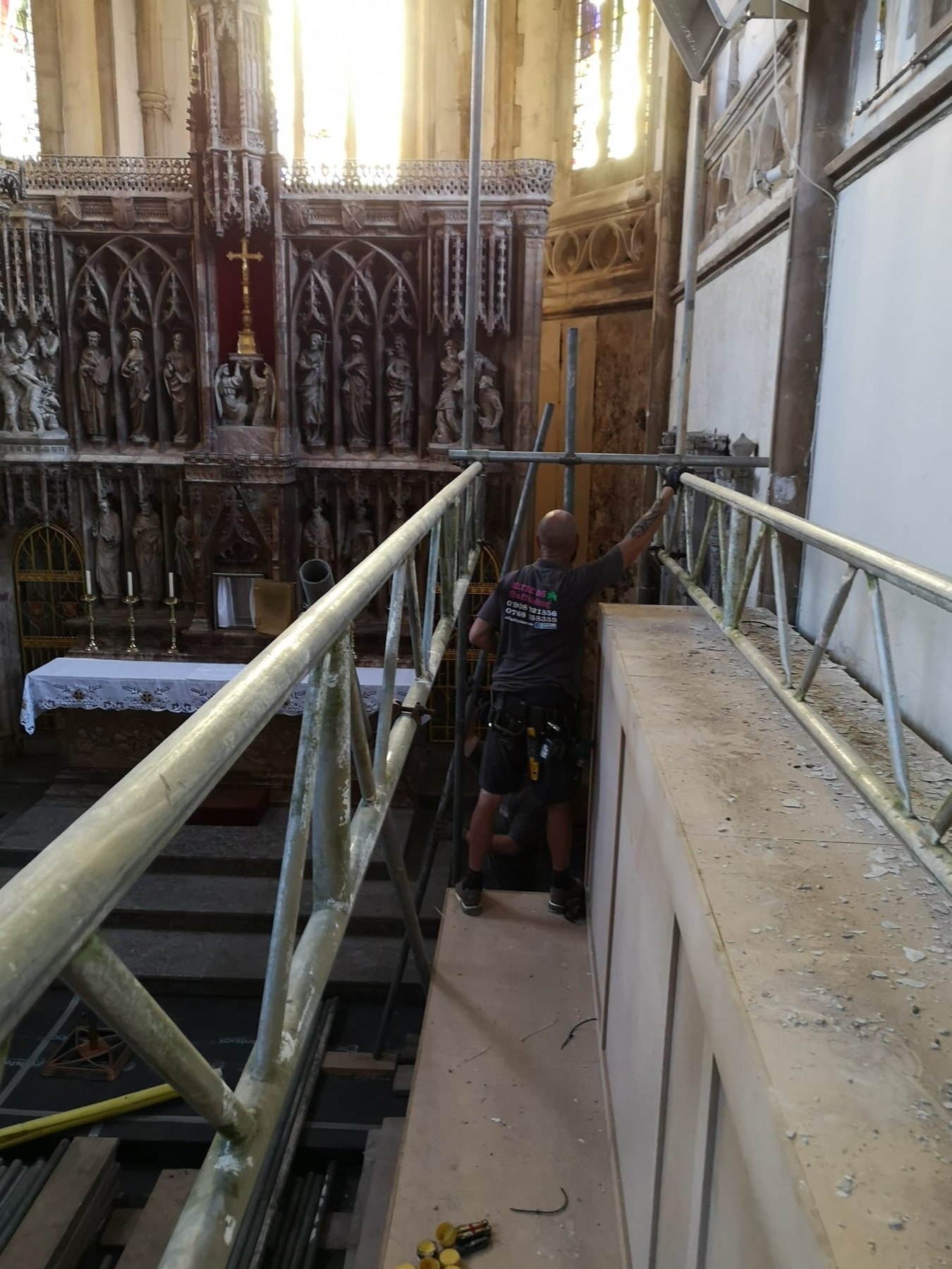 Scaffolder on an internal lift in front of a church reredos